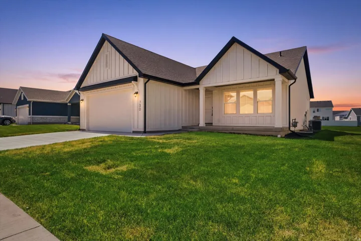 Modern farmhouse exterior with white vertical siding, black trim, a covered porch, a two-car garage, and a concrete driveway