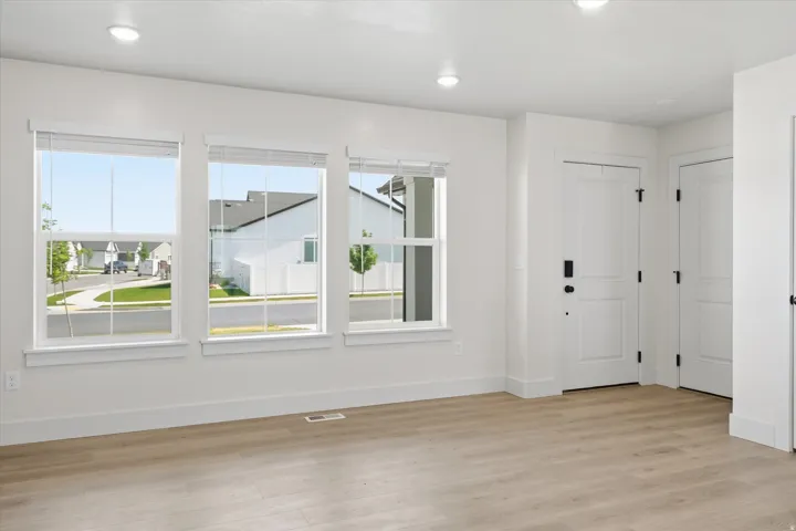 Spacious interior with three large windows, wood-finish flooring, recessed lighting, and white paneled doors