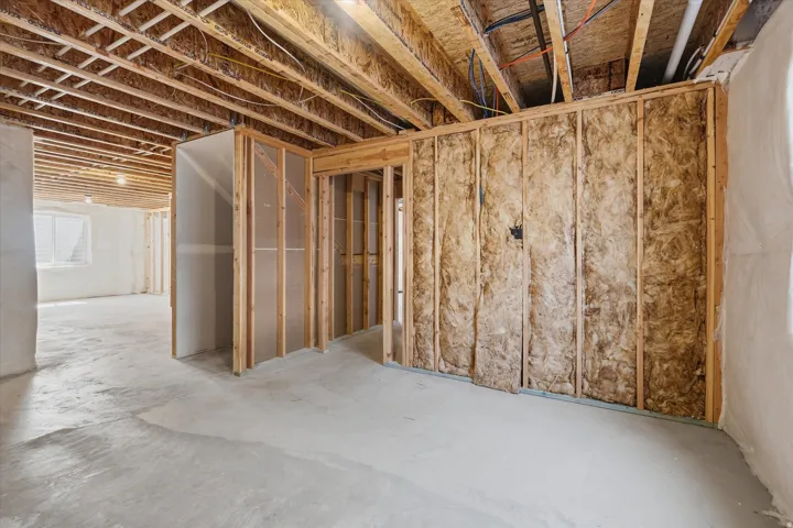 Unfinished basement offering exposed wood framing, concrete flooring, and partial wall insulation