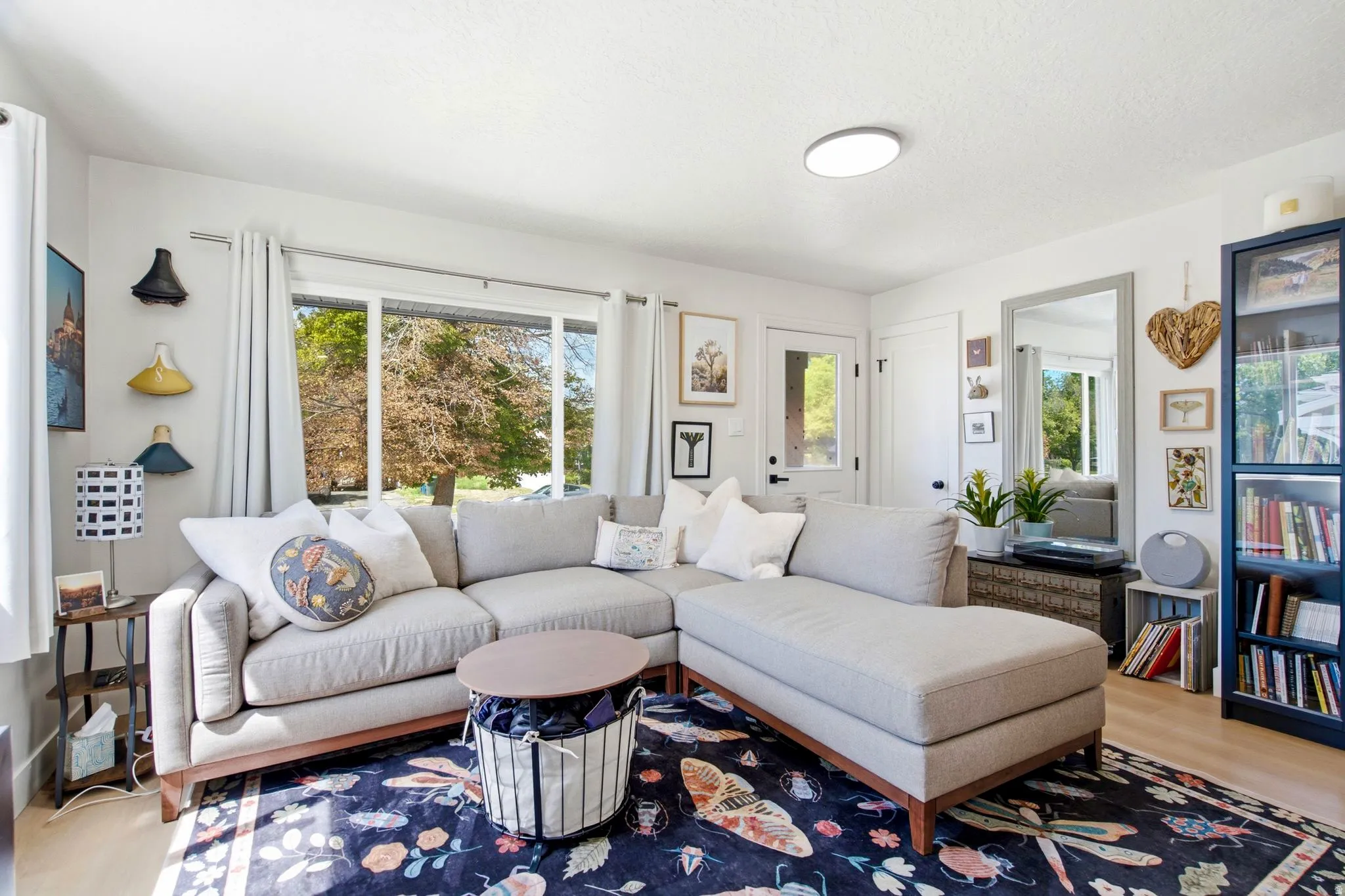 Bright living space featuring a large window, light wood-finish flooring, a white paneled door, and a built-in display cabinet