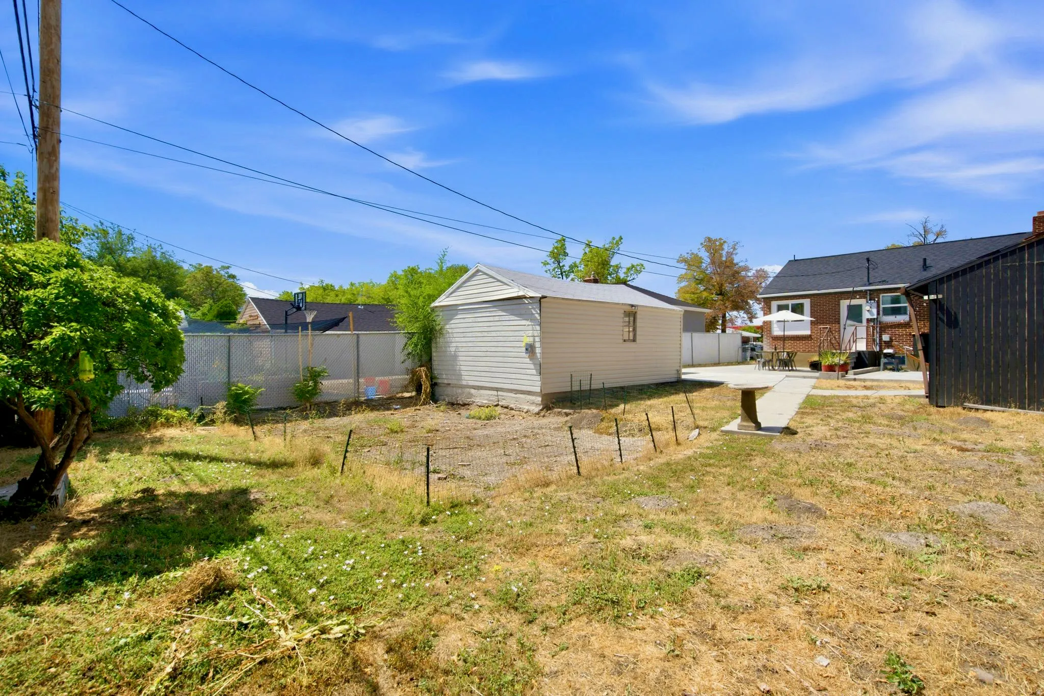 Expansive backyard featuring a concrete patio, a detached storage building, and a privacy fence