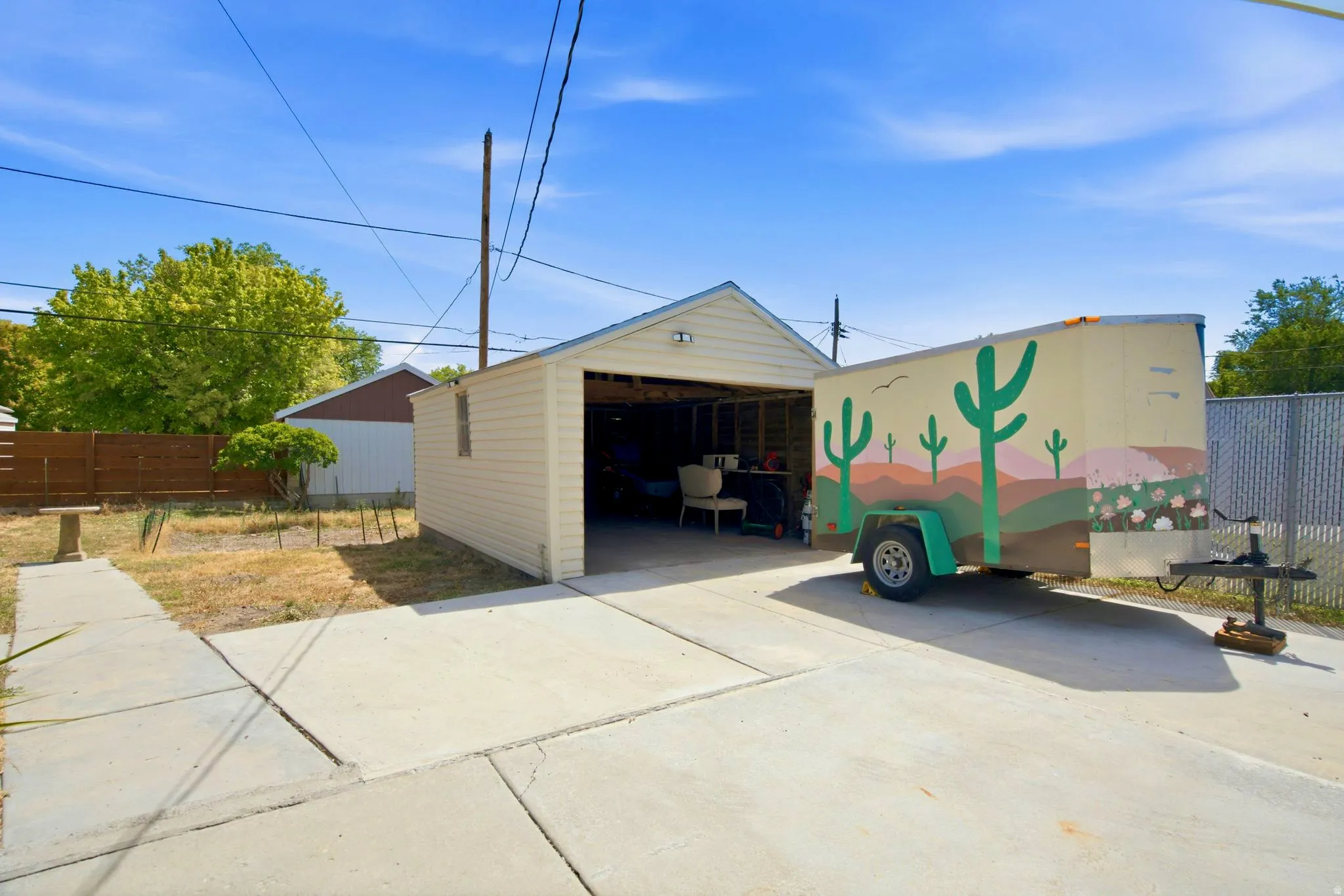 Detached garage with an overhead door, concrete driveway, and concrete patio