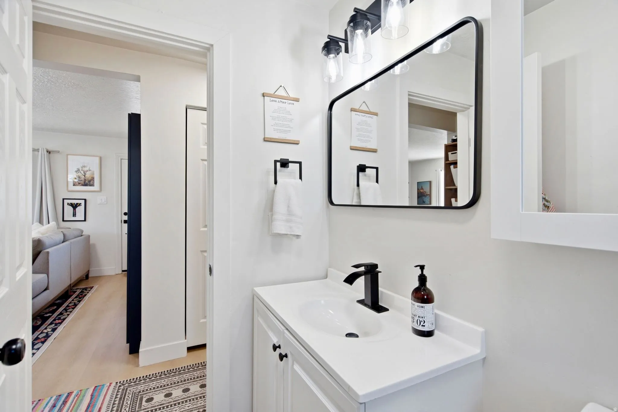 White vanity with an integrated sink, matte black faucet, and coordinating mirror