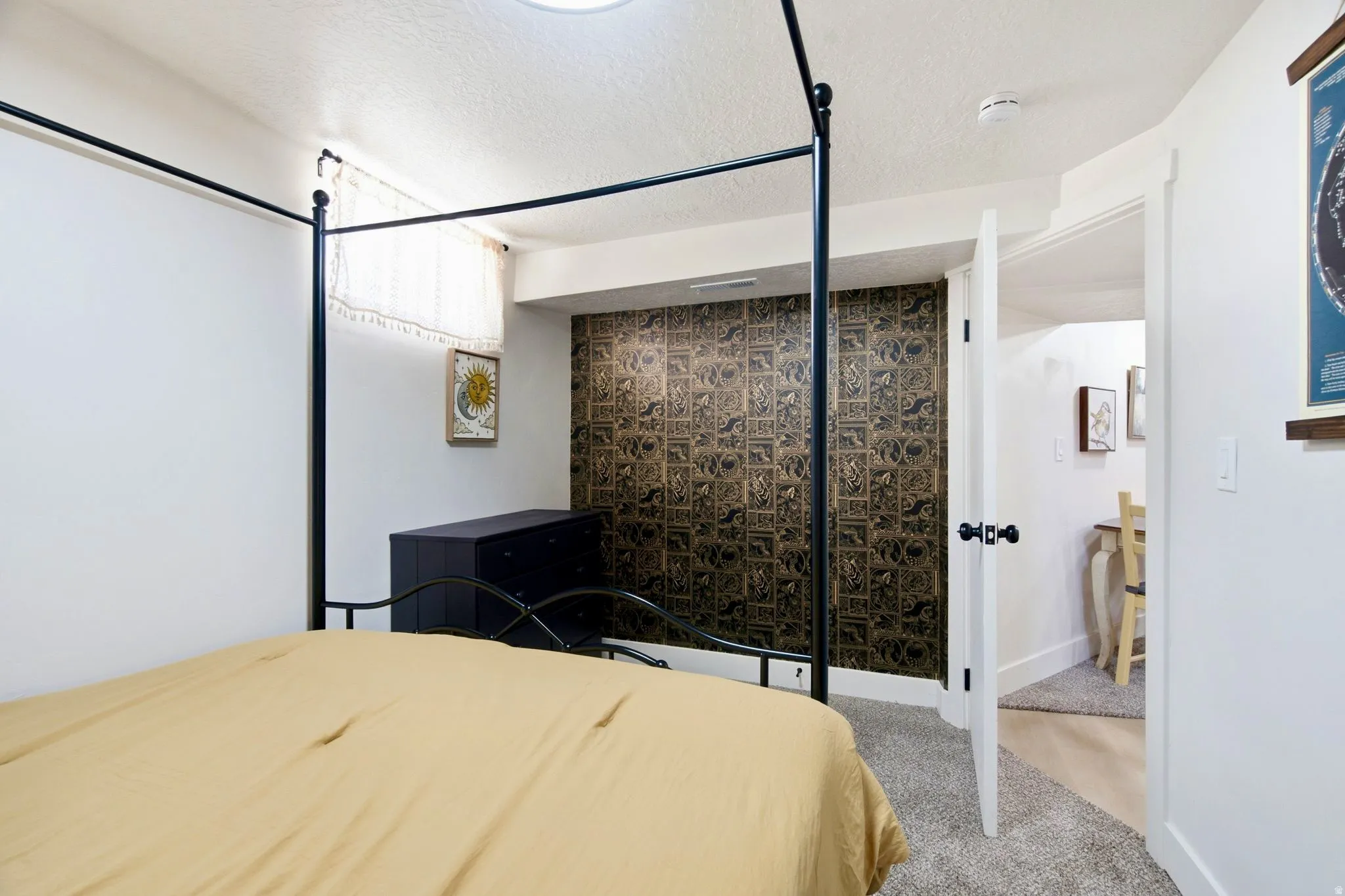 Recessed ceiling lighting, textured wall finish, white interior doors with black hardware, carpet flooring, and a visible doorway to an additional room