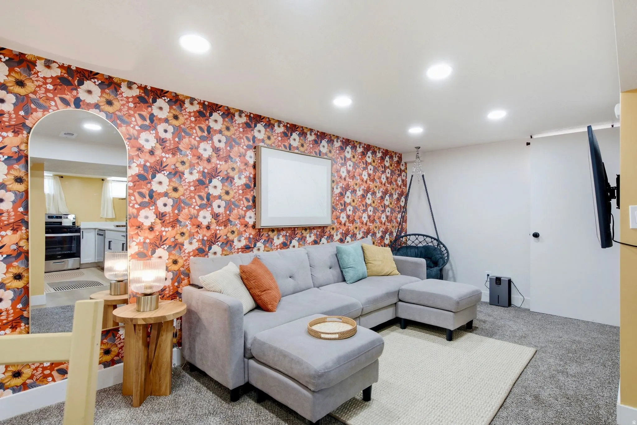 Recessed ceiling lighting, a wall-mounted television, and an arched doorway leading to an additional space