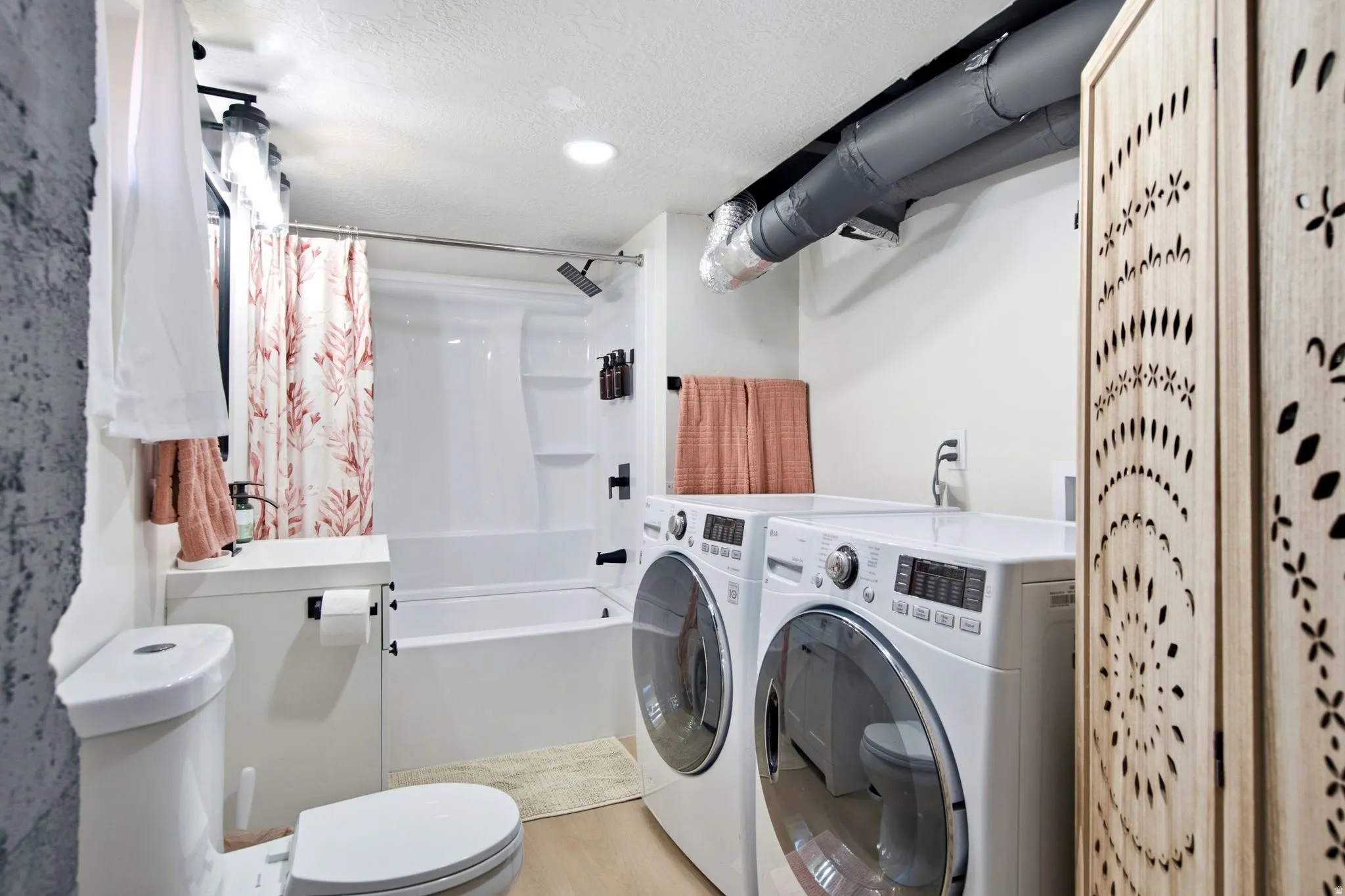 Full-size washer and dryer units, combined bathtub and shower, recessed ceiling lighting, and exposed ductwork