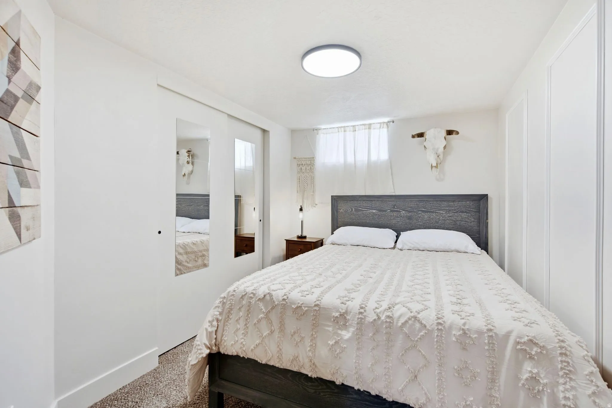 White-painted walls with decorative wall paneling, mirrored sliding closet doors, and wood-finish flooring