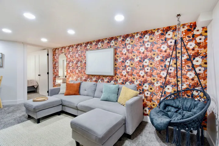 Recessed ceiling lighting, patterned accent wall, and a built-in hanging chair