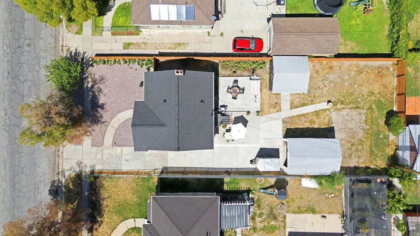 Expansive lot with a main residence, two detached outbuildings, a paved patio, and a gravel front yard with a curved walkway