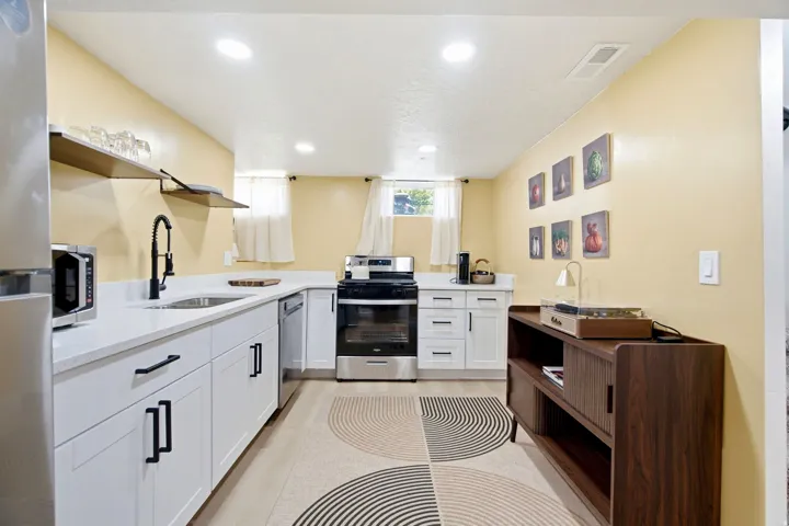 Contemporary kitchen featuring white cabinetry, a stainless steel electric range, a stainless steel dishwasher, white countertops, and wood-finish flooring