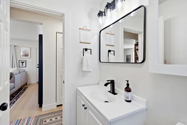 White vanity with an integrated sink, matte black faucet, and coordinating mirror