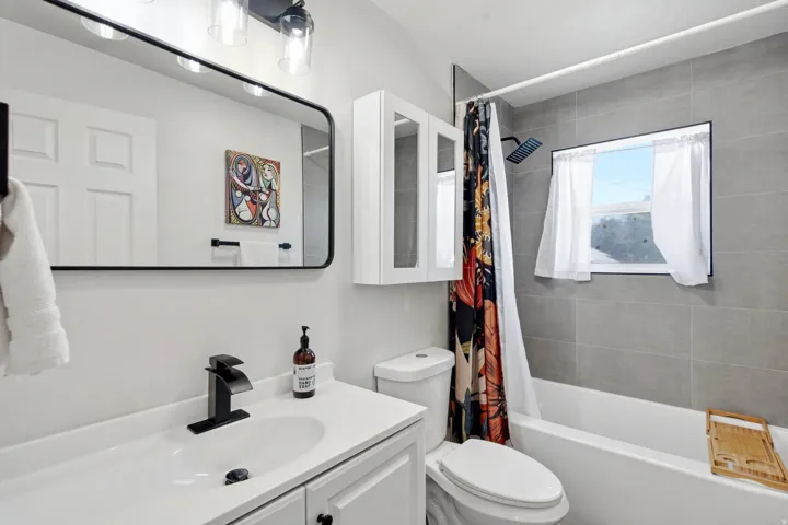 White vanity with a single basin sink and matte black faucet