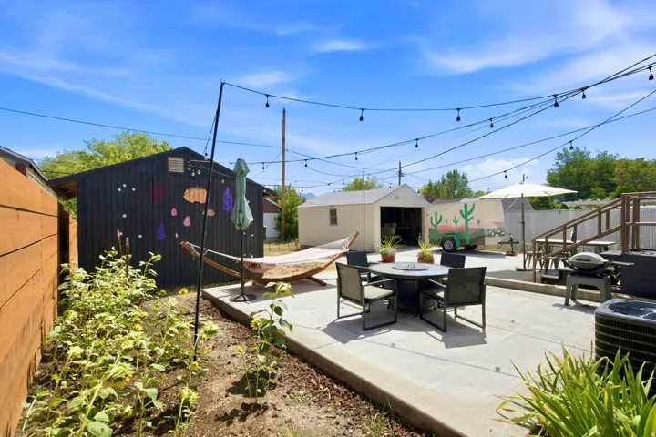 Outdoor concrete patio with string lighting, raised deck, and detached garage
