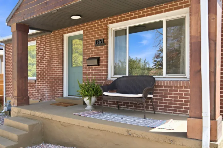 Brick exterior with covered front porch, a light blue door, and white frame windows