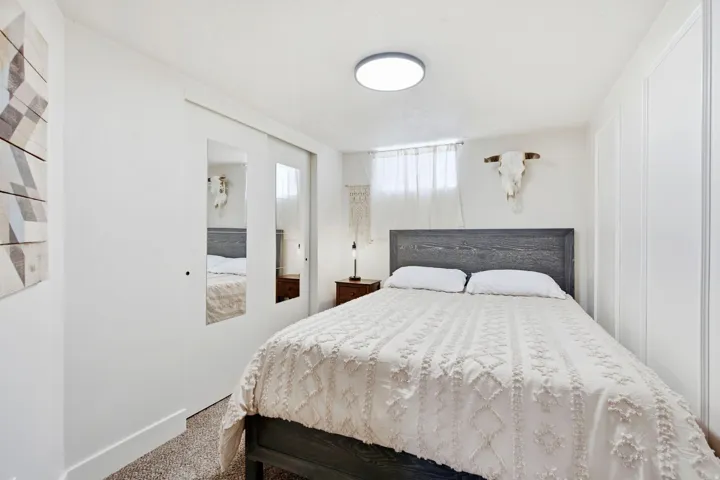 White-painted walls with decorative wall paneling, mirrored sliding closet doors, and wood-finish flooring