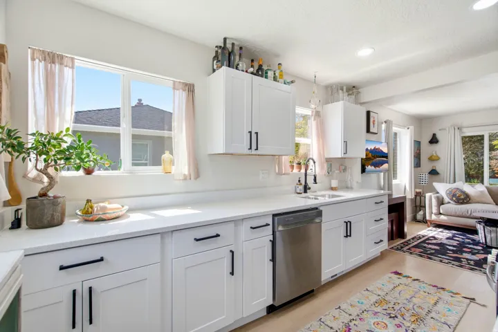 White shaker cabinetry with black hardware, stainless steel dishwasher, white countertops, recessed lighting, and wood-finish flooring