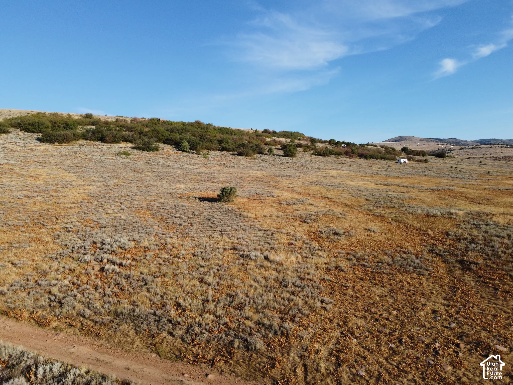 Expansive open land featuring natural vegetation and distant hills