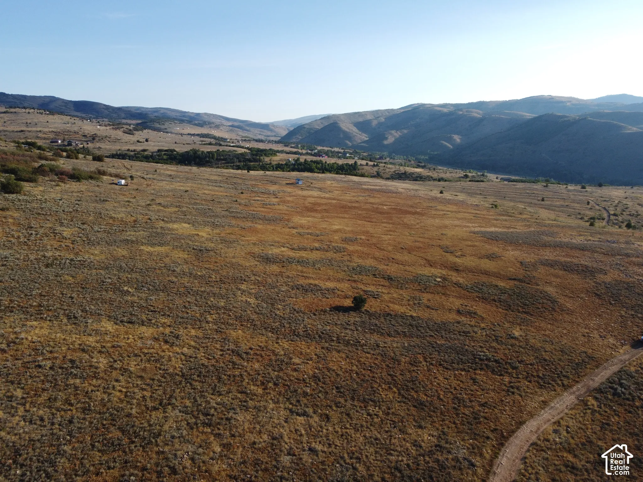 Expansive undeveloped land with a visible unpaved access path and distant mountainous terrain