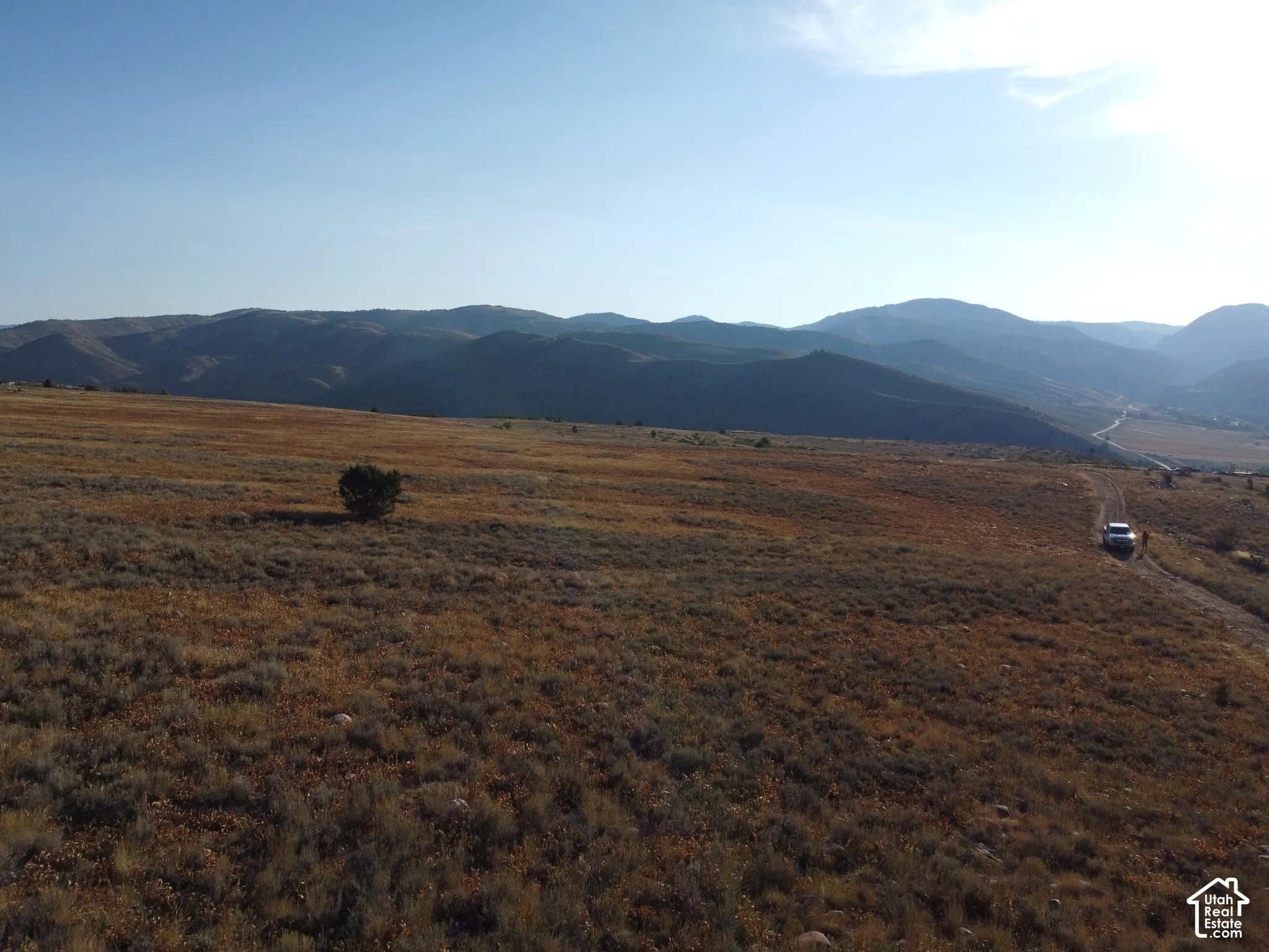 Expansive open land featuring natural vegetation and distant mountain ranges