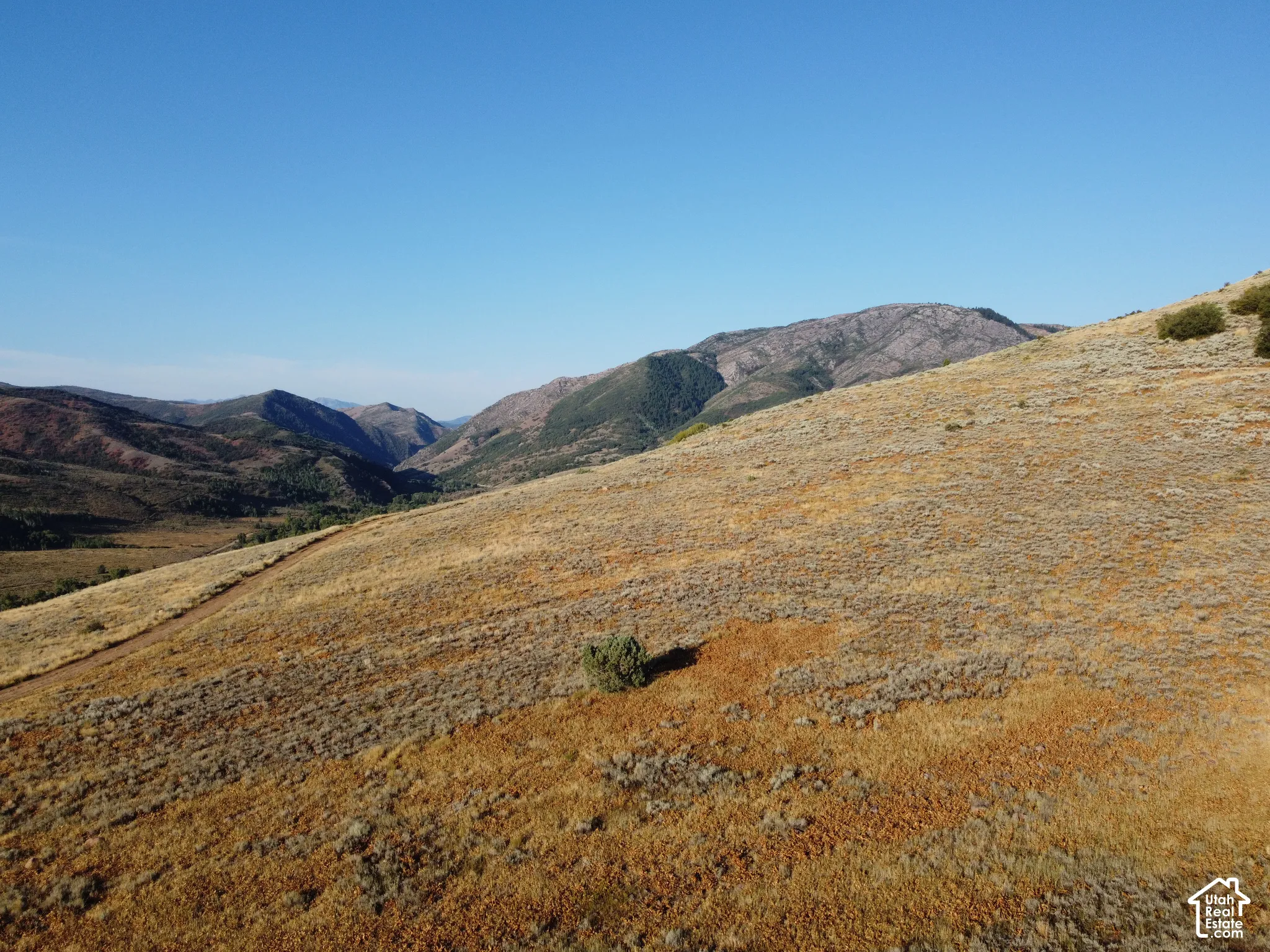 Expansive acreage with natural terrain, distant mountains, and clear skies