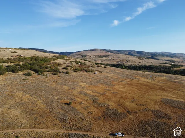 Expansive acreage with rolling hills, natural ground cover, and distant mountainous terrain