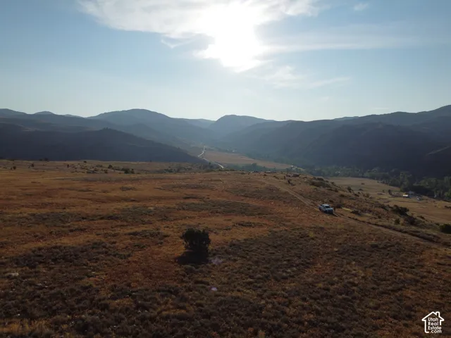 Expansive open terrain featuring natural vegetation, a distant valley, and surrounding mountains