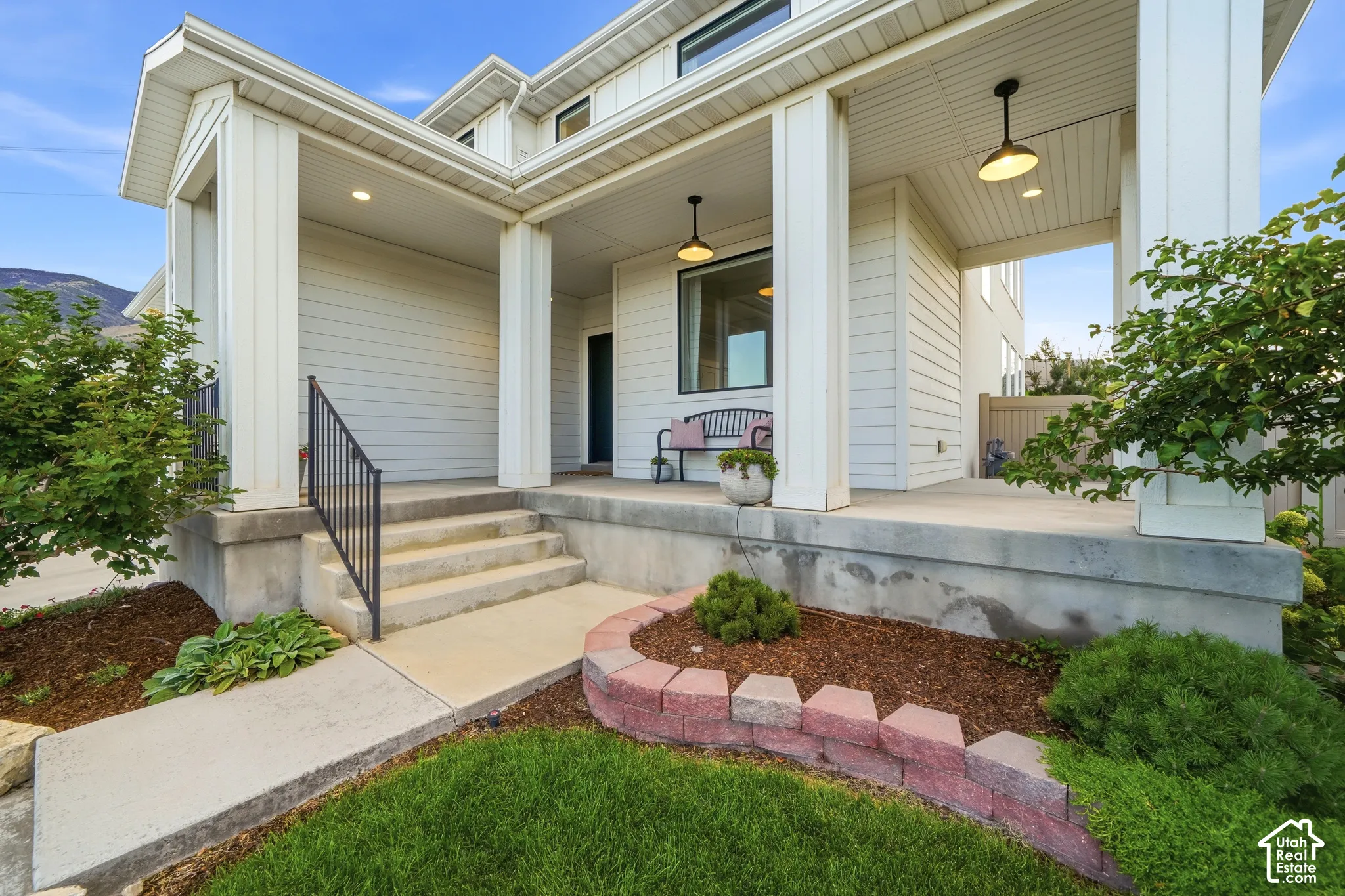 Front exterior featuring a covered porch, white siding, column supports, and pendant lighting