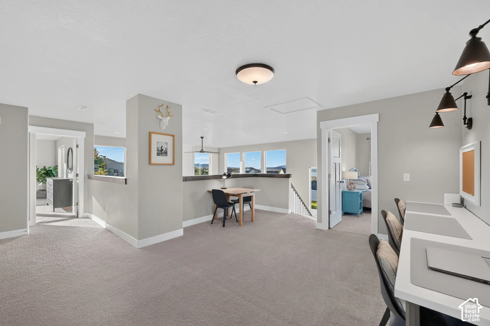 Expansive carpeted loft area with multiple windows, built-in desk space, and recessed lighting