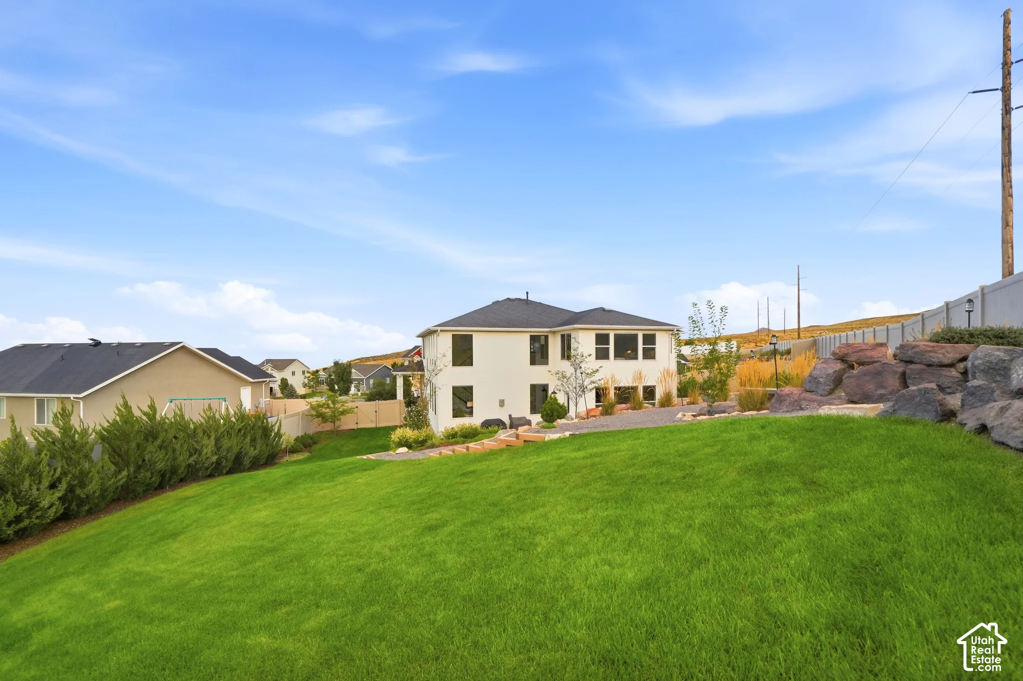 Expansive green lawn with a landscaped rock retaining wall