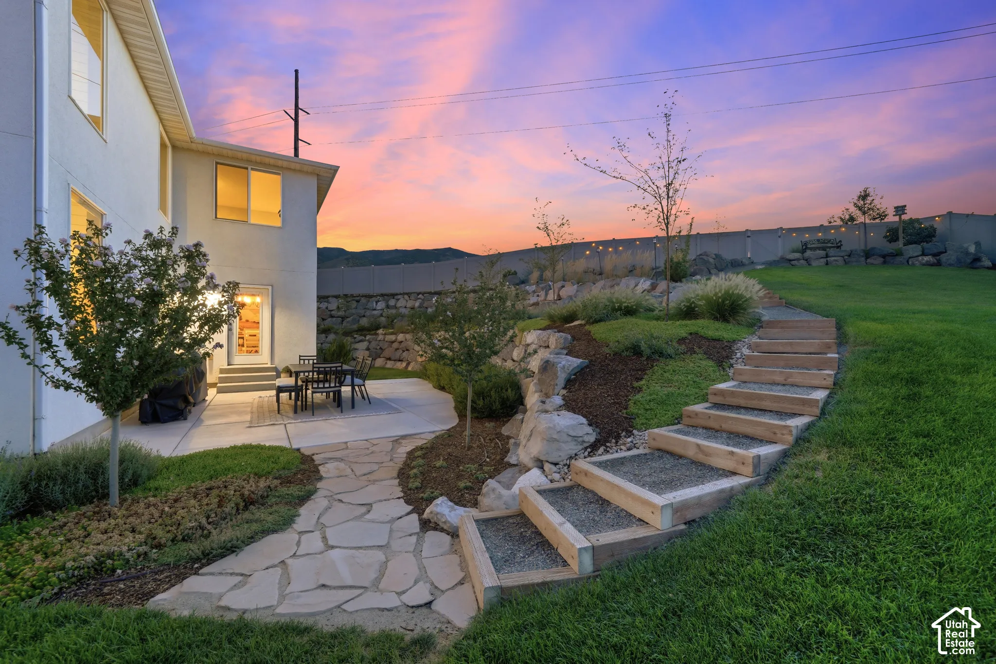 Expansive grass lawn with terraced landscaping and a stone pathway leading to a concrete patio