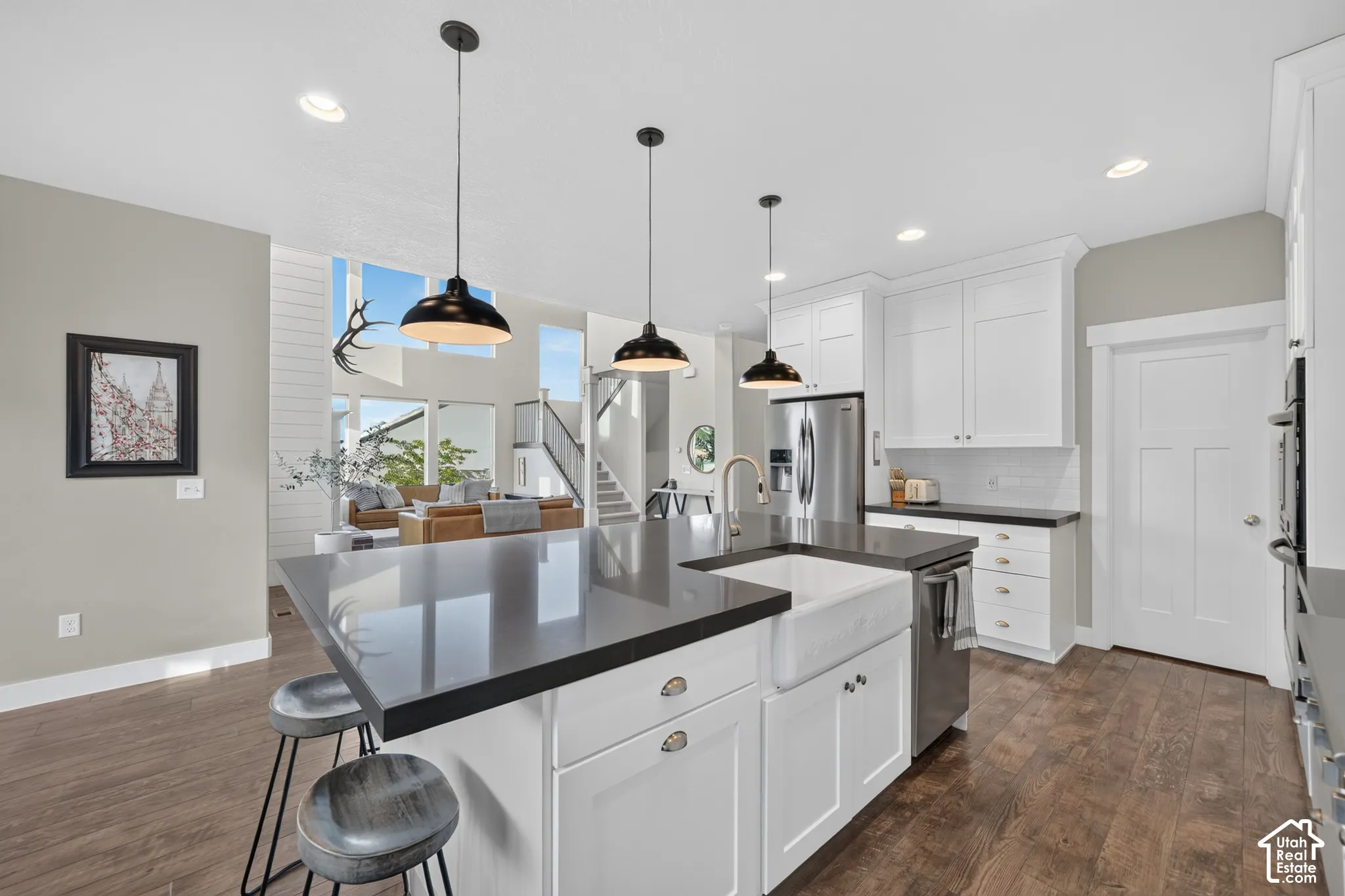 Open-concept kitchen with white shaker cabinetry, dark countertops, a large center island, and integrated stainless steel appliances