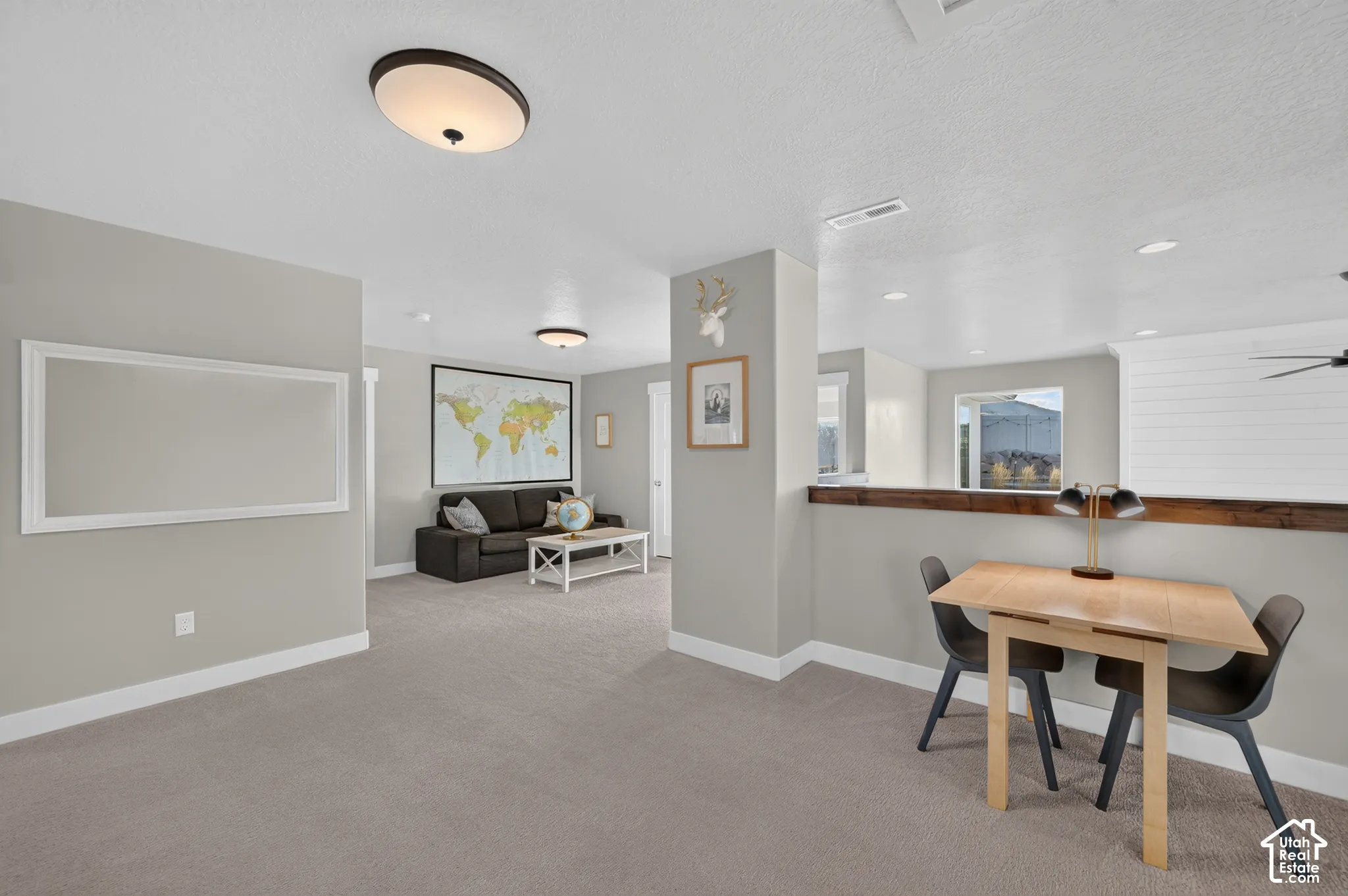 Carpeted open-concept space featuring a half-wall with wood-finish top and ceiling-mounted light fixtures