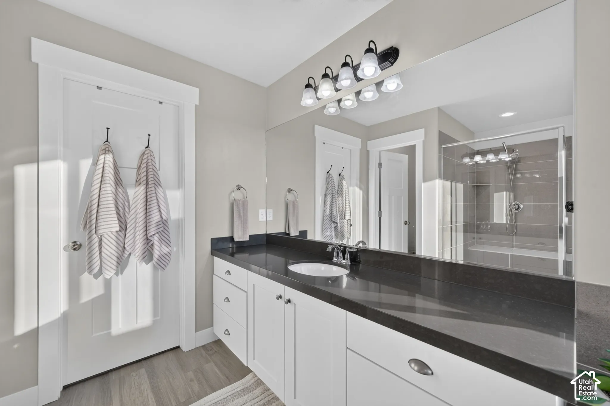 Extended vanity with a dark countertop, undermount sink, and white cabinetry