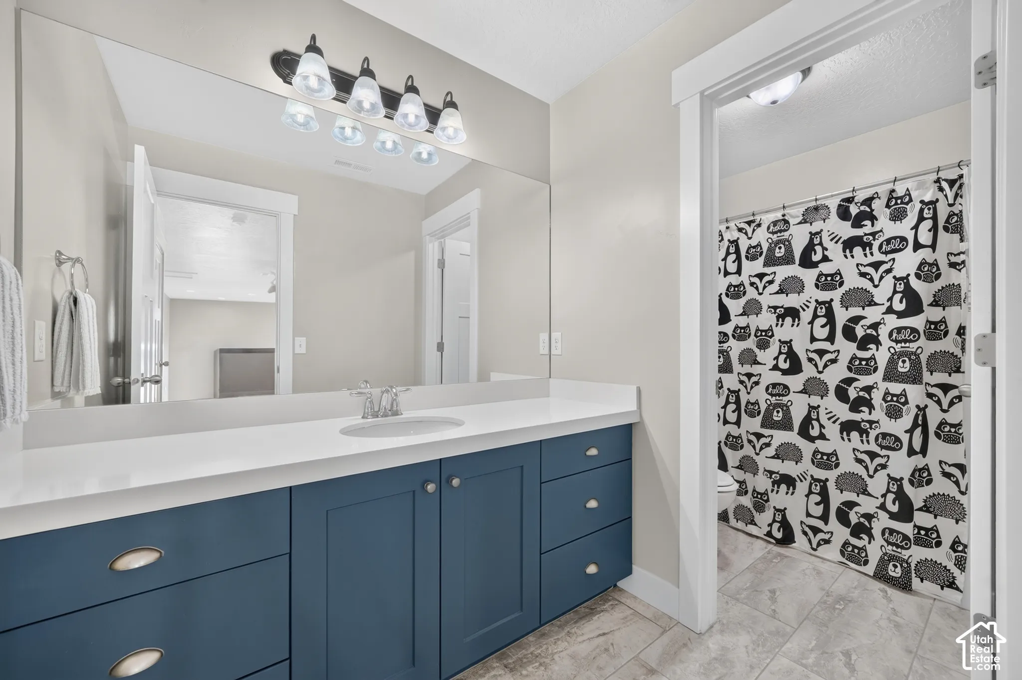 Spacious vanity with blue cabinetry, white countertop, integrated sink, and large wall-mounted mirror