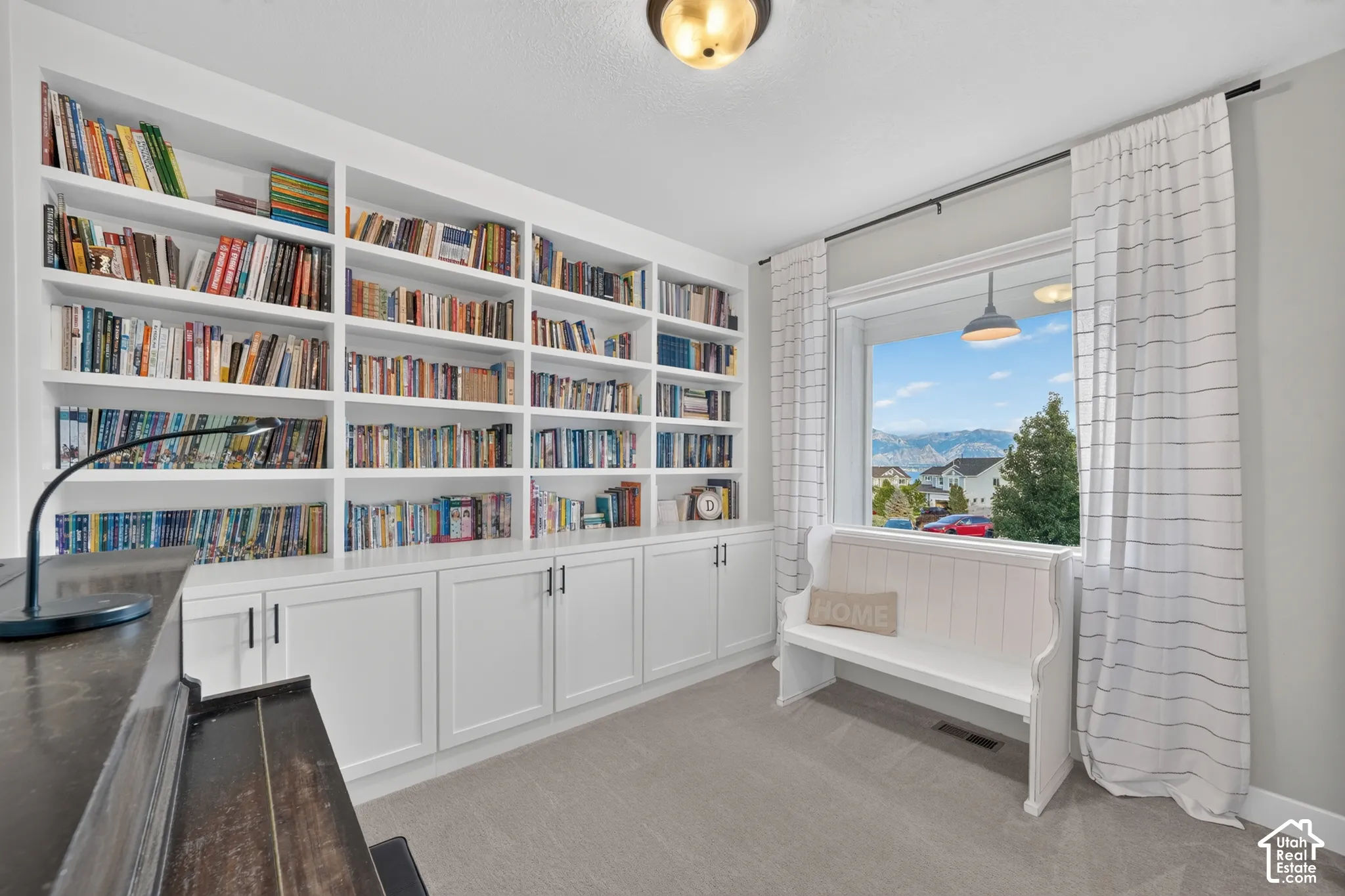 Built-in shelving with lower cabinetry, large window with expansive outdoor scenery, wall-mounted light fixture, and neutral wall color
