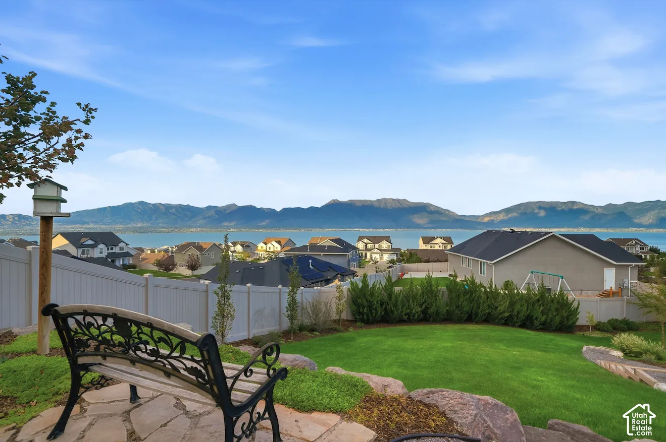 Expansive backyard with a manicured lawn, established shrubs, and natural rock accents