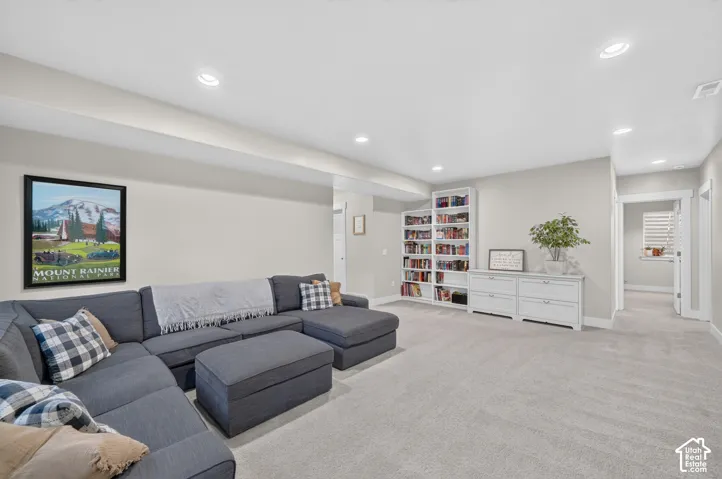 Recessed lighting, light-colored walls, carpeted flooring, built-in shelving, and a built-in storage unit