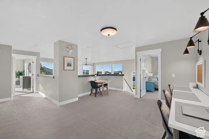 Expansive carpeted loft area with multiple windows, built-in desk space, and recessed lighting