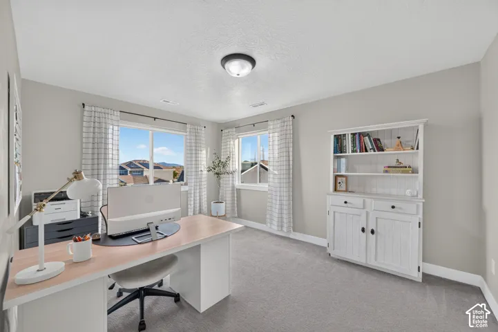 Neutral-toned walls, two large windows, plush carpeting, and a built-in white storage unit with shelving