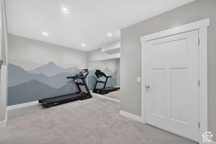 Recessed lighting illuminates a space featuring a decorative mountain mural and full-wall mirrors