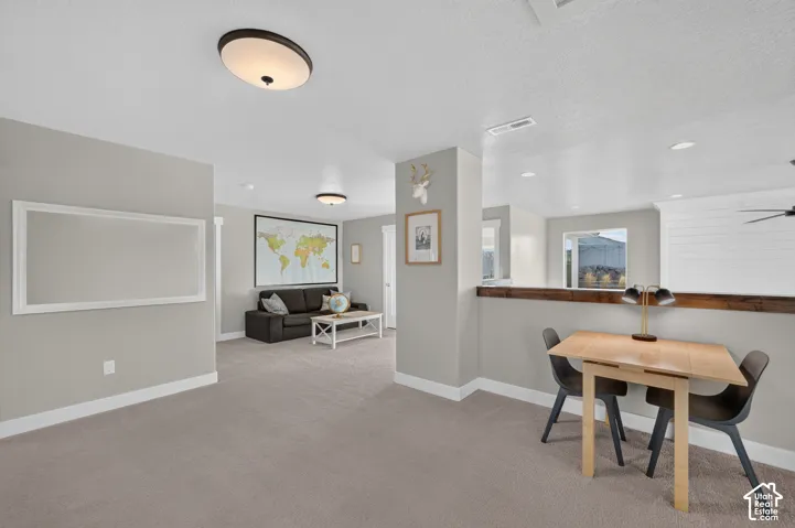 Carpeted open-concept space featuring a half-wall with wood-finish top and ceiling-mounted light fixtures