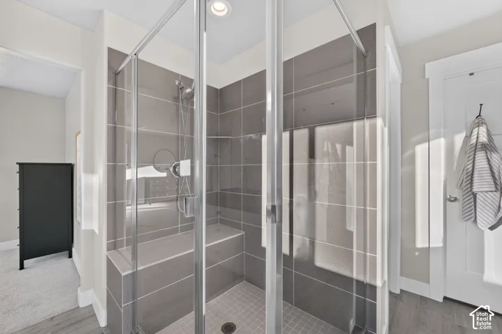 Glass-enclosed shower with gray tile surround, integrated bench seating, and recessed lighting