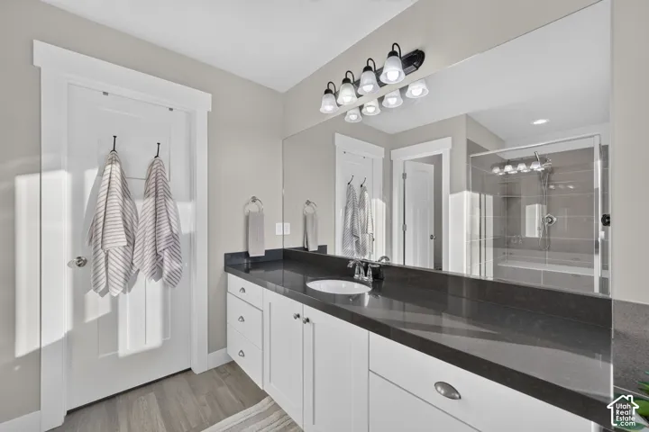 Extended vanity with a dark countertop, undermount sink, and white cabinetry