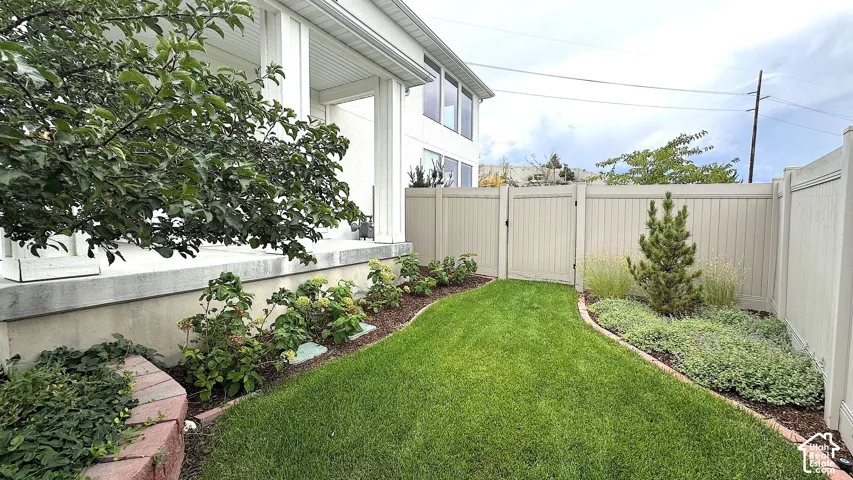 Expansive side yard featuring a lush lawn, established plantings, and a privacy fence with a gate