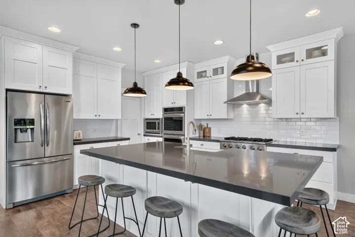 Kitchen featuring white shaker cabinetry, stainless steel appliances, a center island with a dark countertop, white subway tile backsplash, and recessed lighting