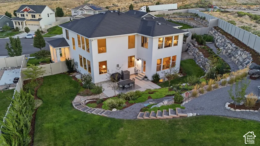 Expansive rear exterior with multiple windows, concrete patio, and terraced landscaping