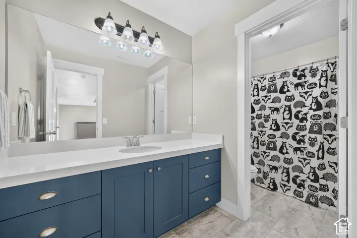 Spacious vanity with blue cabinetry, white countertop, integrated sink, and large wall-mounted mirror