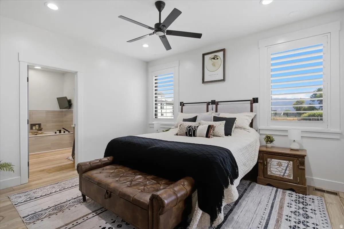 Recessed lighting, ceiling fan, wood-finish flooring, white plantation shutters, and an attached full bathroom
