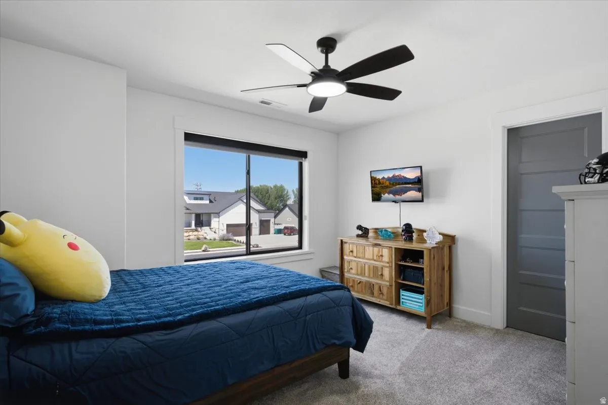 Recessed ceiling fan with integrated lighting, expansive window with black trim, wall-mounted television, and light gray carpeting
