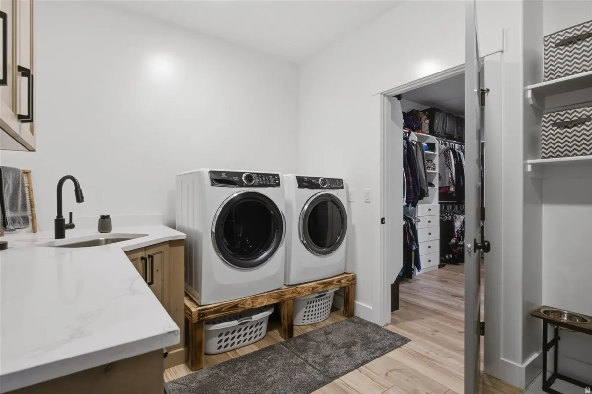 Laundry area featuring a built-in sink with a matte black faucet, light wood-finish cabinetry, and white countertops